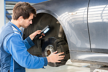 Image showing Mechanic Examining Brake Disc Of Car In Garage