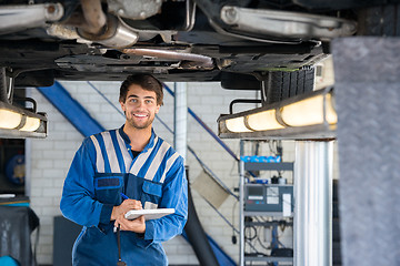 Image showing Happy Mechanic Writing On Clipboard Under Car