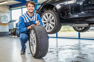Image showing Mechanic Pressing Gauge Into Tire Tread In Garage