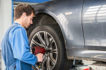 Image showing Mechanic Changing Wheel On Car With Pneumatic Wrench