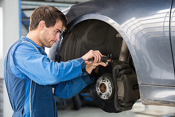 Image showing Car Mechanic Examining Brake Disc With Caliper