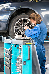 Image showing Mechanic Changing Tire From Suspended Car In Garage