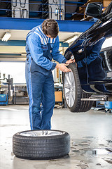 Image showing Mechanic Pressing Gauge Into Tire Tread To Measure Its Depth
