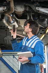 Image showing Mechanic checking an exhaust for gas leaks