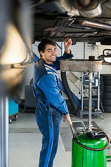 Image showing Smiling Mechanic Repairing Car On Hydraulic Lift