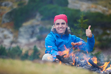 Image showing hiking man prepare tasty sausages on campfire