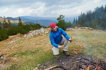 Image showing hiking man prepare tasty sausages on campfire