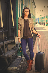 Image showing beautiful woman standing with luggage near the vintage railcar