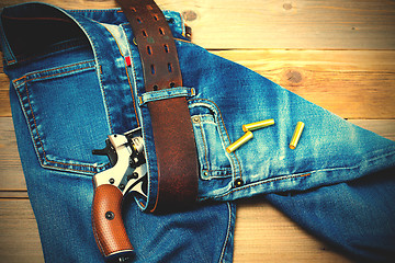 Image showing revolver nagant with cartridges in old blue jeans