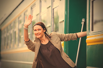 Image showing smiling woman waving from the departing train