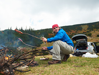 Image showing hiking man prepare tasty sausages on campfire