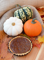 Image showing Small pumpkin pie with leaves and gourds