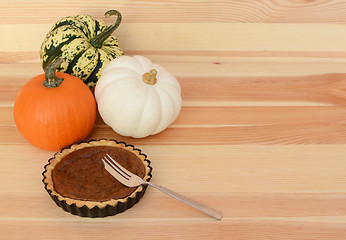 Image showing Three pumpkins with small pumpkin pie and fork