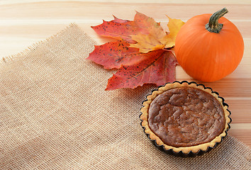 Image showing Small pumpkin pie with gourd and autumn leaves