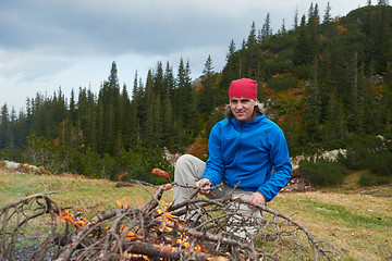 Image showing hiking man prepare tasty sausages on campfire