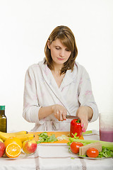 Image showing Young woman cuts sweet pepper vegetarian cooking Salad