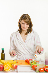 Image showing Housewife throws sliced peppers in a bowl of salad