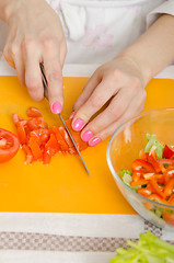 Image showing Girl cuts a tomato for a vegetable salad