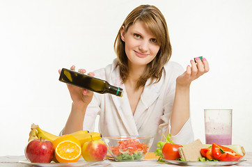 Image showing Young girl pours oil into a vegetarian vegetable vitamin salad