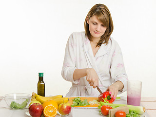 Image showing Young girl cuts pepper vegetarian salad