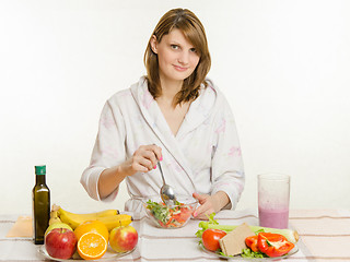 Image showing Young girl stirs cooked vegetarian vegetable salad