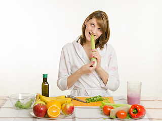 Image showing Happy housewife biting celery and looking up