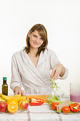 Image showing Housewife throws chopped celery in a bowl of salad