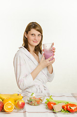 Image showing Young girl sitting at the kitchen table, drinking a vitamin milkshake