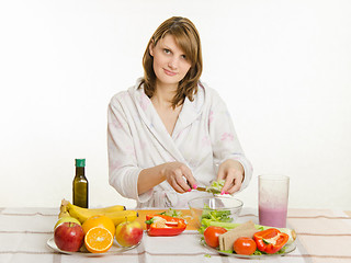 Image showing Housewife holds over a cup of salad with chopped vegetables