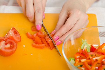 Image showing Close up of a female hand cutting tomatoes for cooking vegetable salad