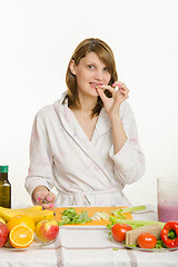 Image showing A young girl tries to slice vegetarian chopped celery for vegetable salad