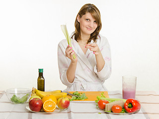 Image showing Happy housewife cleans the rind salad with celery cooking