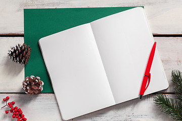 Image showing The open notebook on the wooden table with a pen