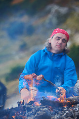 Image showing hiking man prepare tasty sausages on campfire