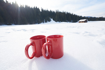 Image showing two red coups of hot tea drink in snow  at winter