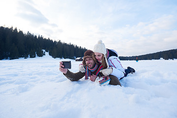 Image showing romantic couple have fun in fresh snow and taking selfie