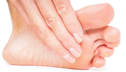 Image showing Person having pedicure, pulling hand under foot towards white ba