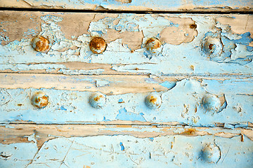 Image showing dirty stripped paint in  blue wood door   rusty nail