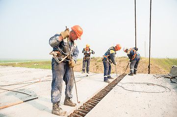 Image showing Builders with metal crow bar installing concrete panel