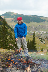 Image showing hiking man prepare tasty sausages on campfire