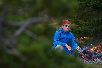 Image showing hiking man prepare tasty sausages on campfire