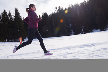 Image showing yougn woman jogging outdoor on snow in forest