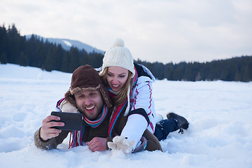 Image showing romantic couple have fun in fresh snow and taking selfie