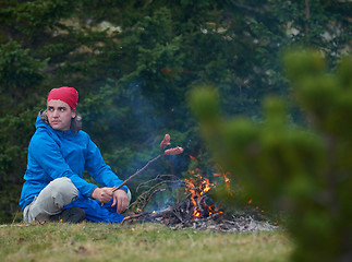 Image showing hiking man prepare tasty sausages on campfire