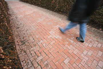 Image showing People passing by a brick wall