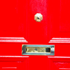 Image showing red handle in london antique brown door  rusty  brass nail and l