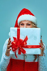 Image showing Girl dressed in santa hat with a Christmas gift 