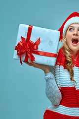 Image showing Girl dressed in santa hat with a Christmas gift 