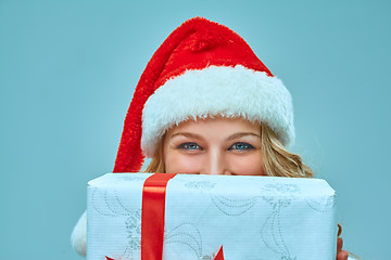 Image showing Girl dressed in santa hat with a Christmas gift 