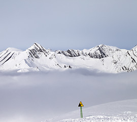 Image showing Mountains in mist and warning sing on ski slope